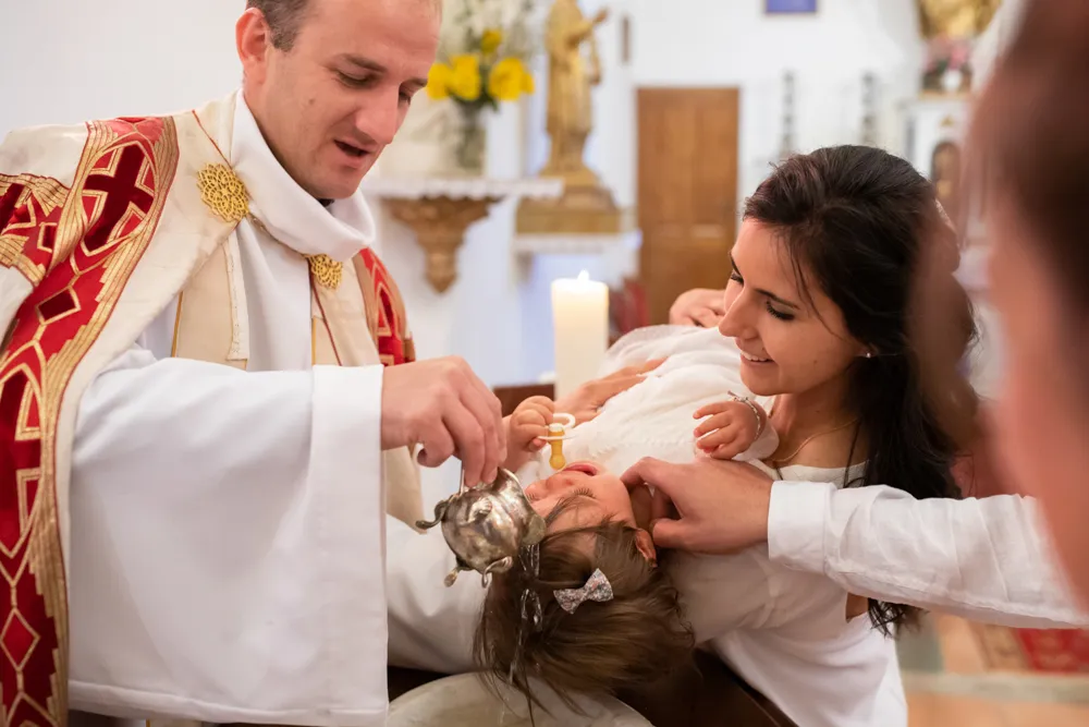 Reportage photo, une petite fille reçoit le baptême baptême