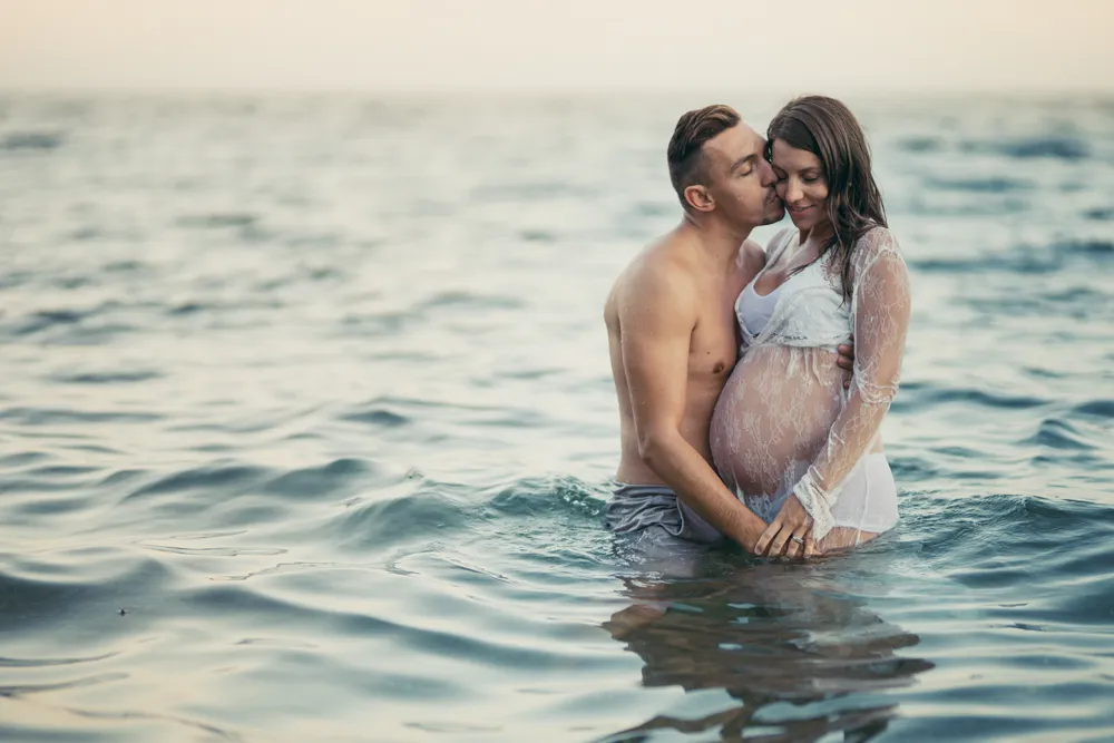 Une future maman et le papa pose dans l'eau à l'occasion d'une séance photo grossesse à la plage dans le Var