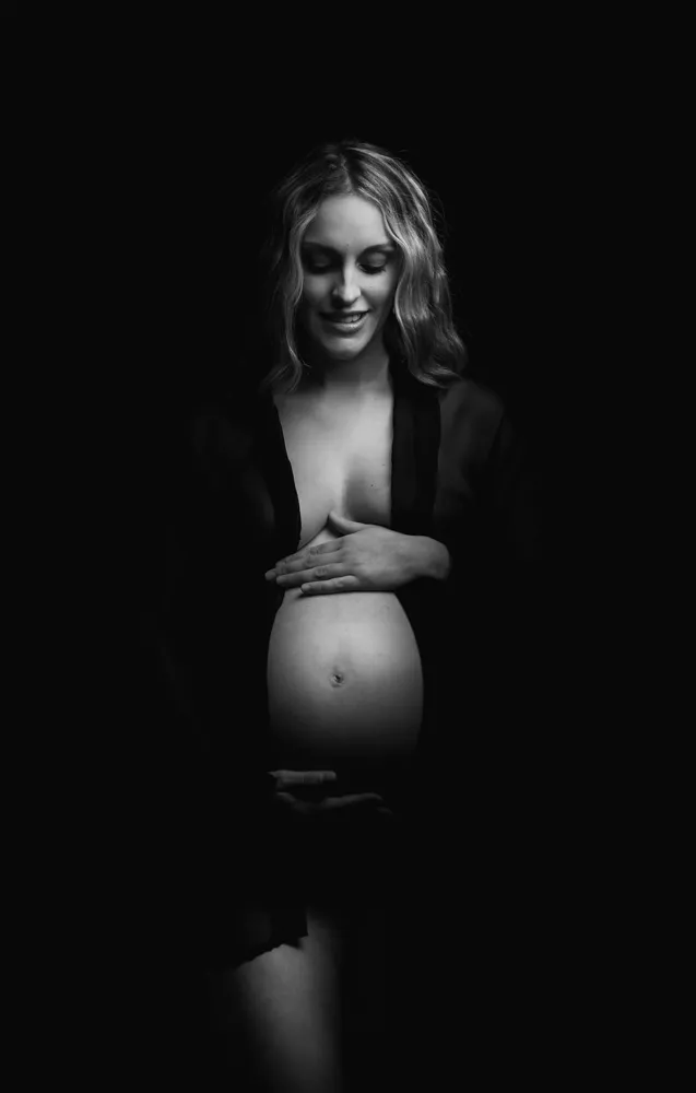 Future Maman pose pose pour une séance grossesse en studio photo en noir et blanc