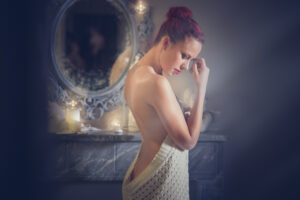 Séance photo boudoir, une jeune femme pose à moitié dévêtue. Elle se tient devant un miroir. le studio photo de Draguignan
