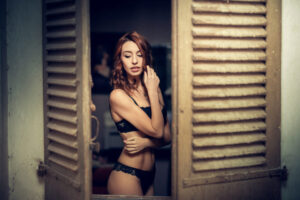 Une femme pose en lingerie à travers une fenêtre pour un shooting photo à Draguignan