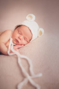 Un bébé avec un bonnet dort lors de la séance photo nouveau-né à Draguignan