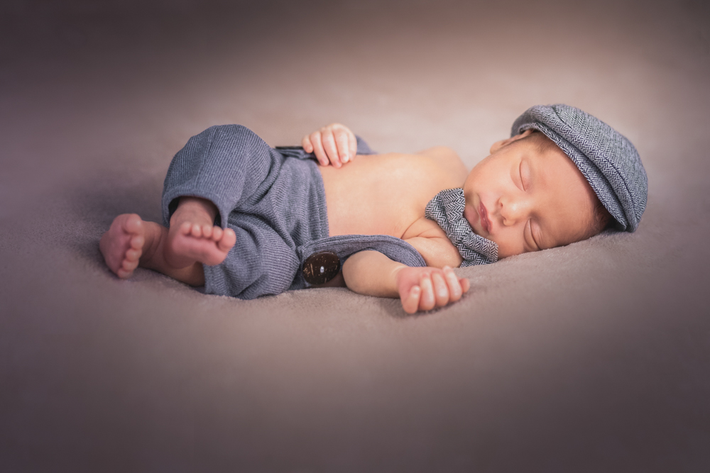 Un bébé en tenue dort lors de la séance photo nouveau-né à Draguignan