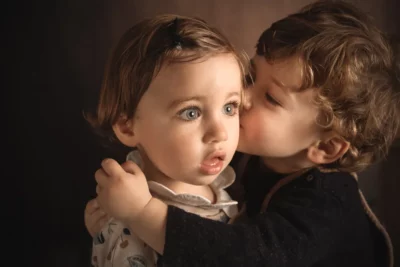 Un grand frère fait un bisou à sa petite soeur à l'occasion de la séance photo en famille à Draguignan