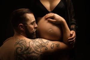 un futur papa enlace le ventre arrondie de sa femme pour une séance maternité à Draguignan