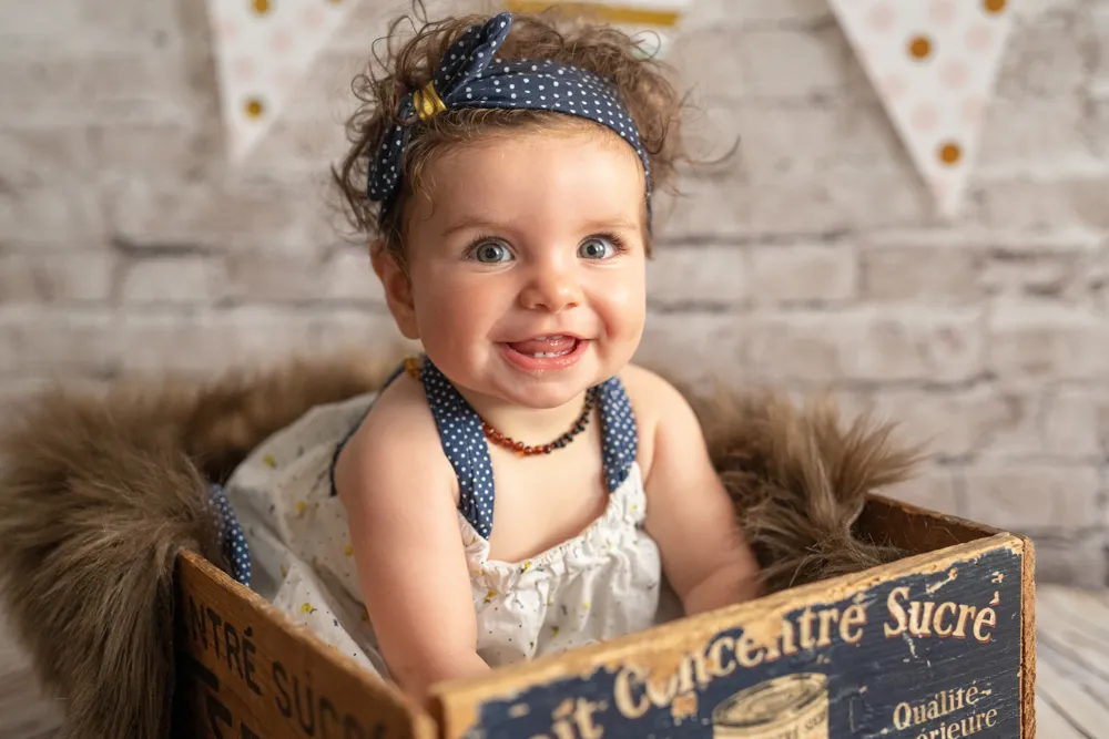 Une jolie petite fille pose dans une caisse en bois pour une séance photo à Draguignan