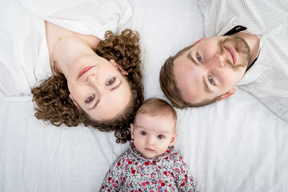 papa, maman, bébé pose pour une séance photo à Draguignan. Ils sont allongé sur le dos