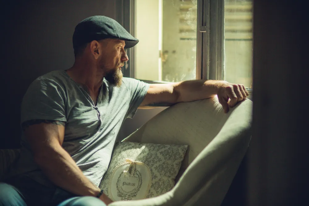 portrait d'un homme assis qui regarde par la fenêtre avec une casquette à Draguignan