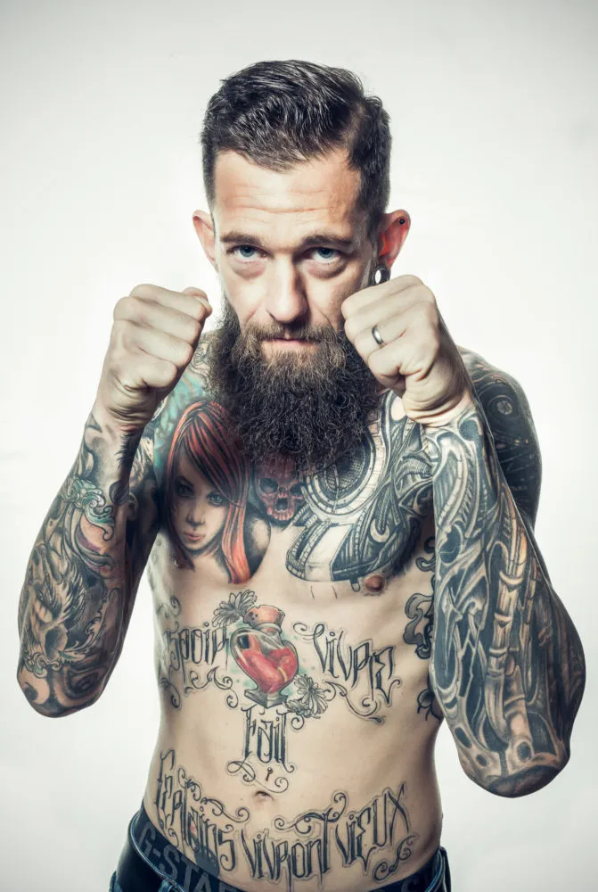 portrait d'un homme tatoué posant torse nu les points en avant à Draguignan