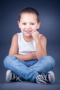 portrait d'un petit garçon souriant assis en tailleur lors d'un shooting photo à Draguignan